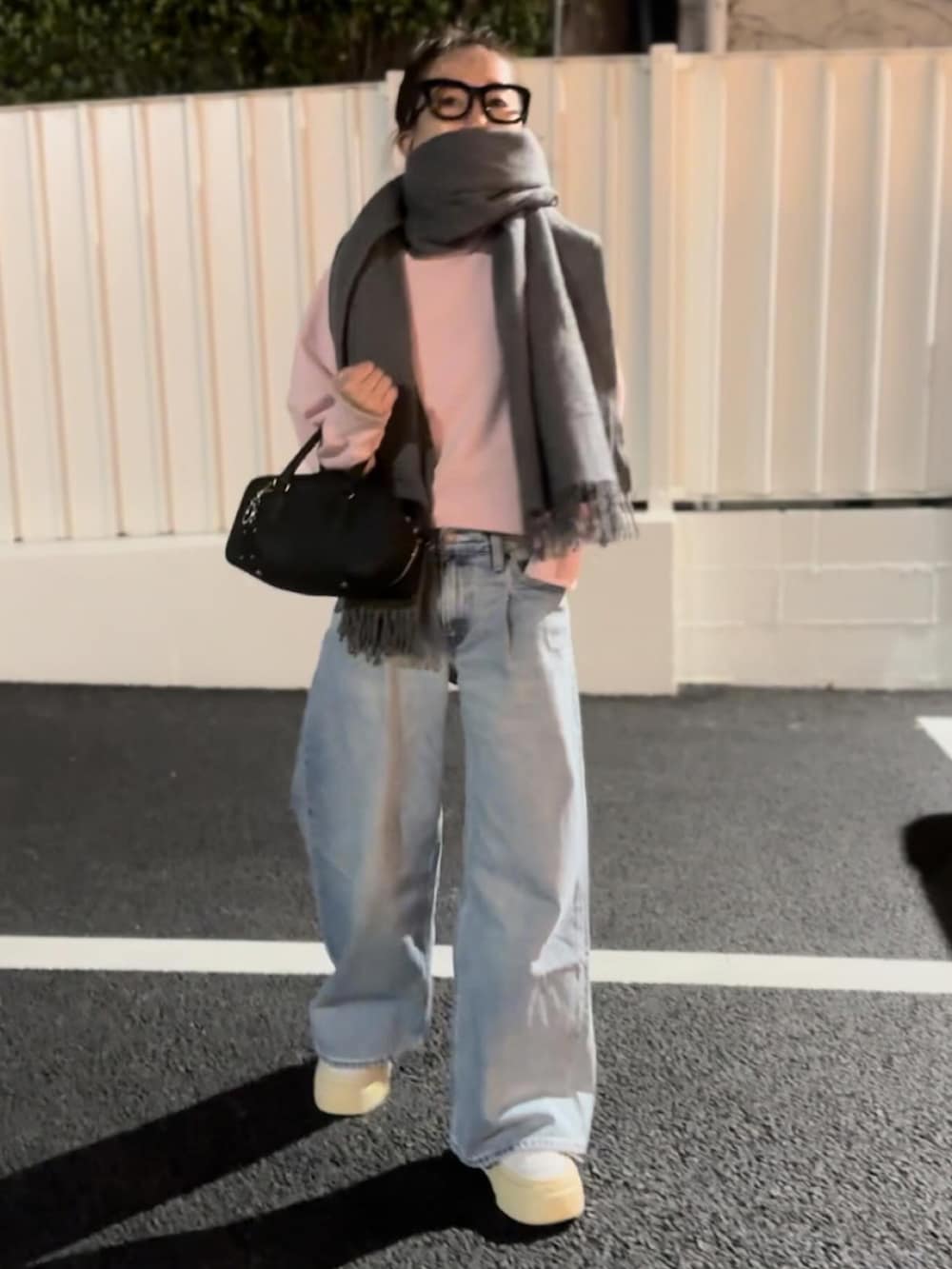 ピンク系のスウェット、ブルー系のデニムパンツ、ホワイト系のスニーカーを着用したレディースの春コーディネートの2枚目の写真