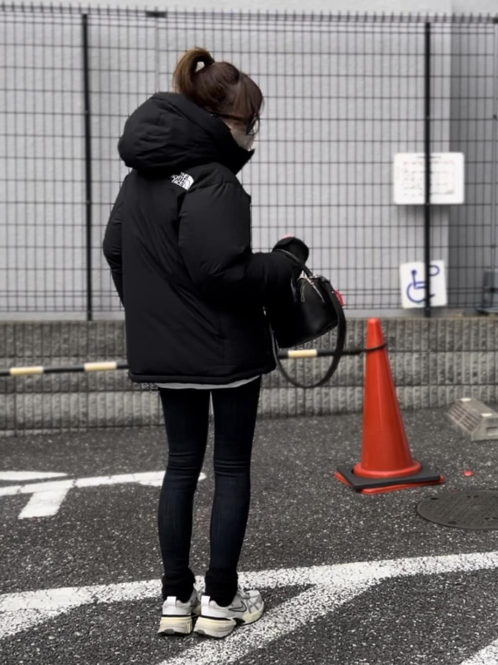 ブラック系のボストンバッグ、ホワイト系のスニーカー、ブラック系のダウンジャケット/コートを着用したレディースの冬コーディネートの2枚目の写真