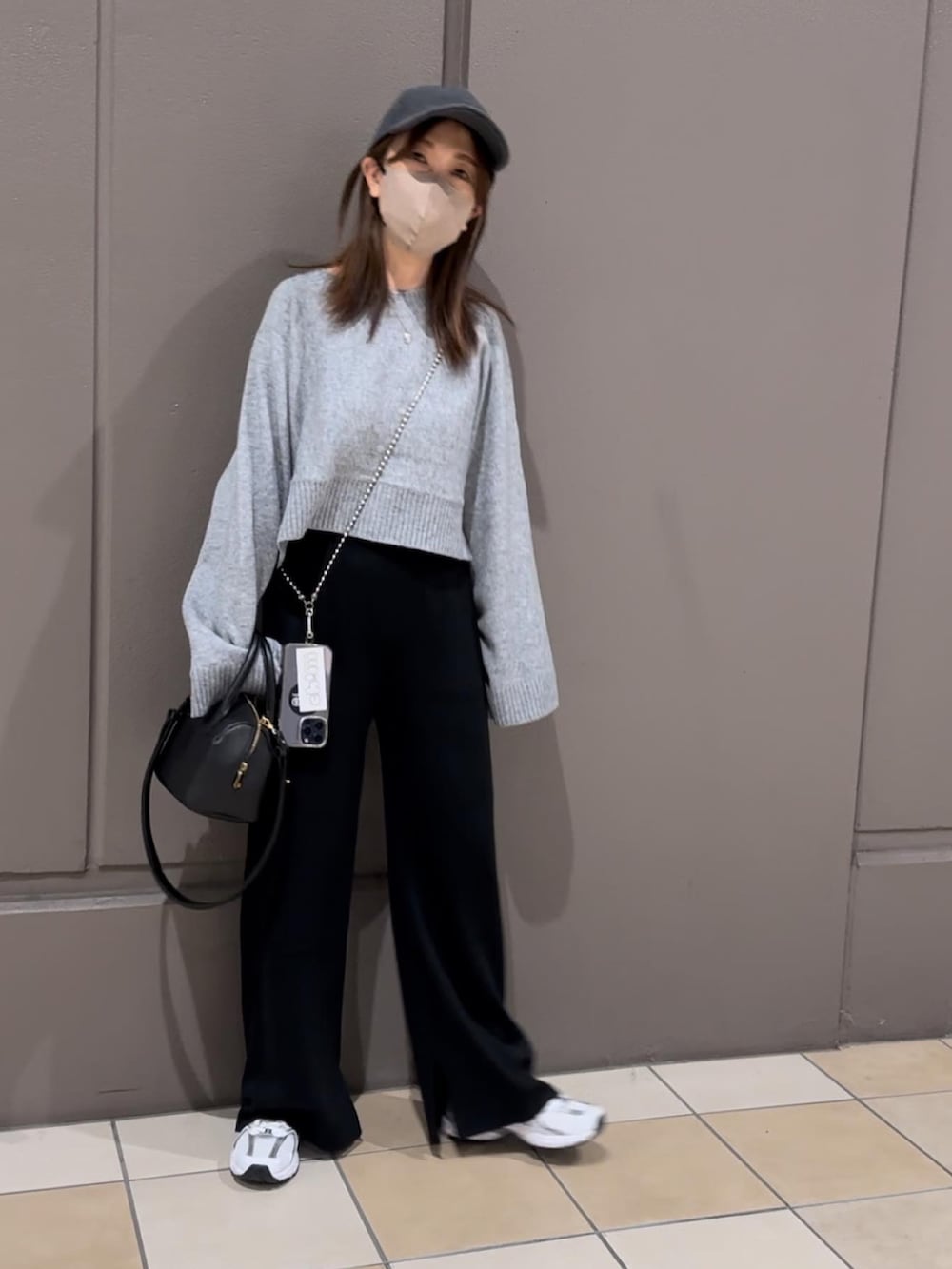 グレー系のニット/セーター、ホワイト系のスニーカー、ブラック系のボストンバッグを着用したレディースの秋コーディネートの2枚目の写真
