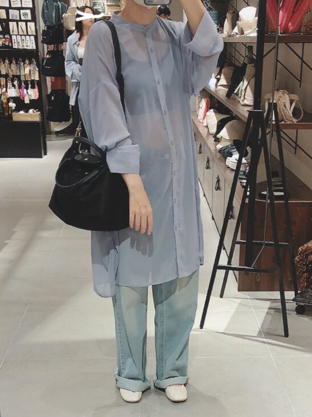 ブラック系のトートバッグ、ブルー系のトップス、ブルー系のデニムパンツを着用したレディースの夏コーディネートの2枚目の写真