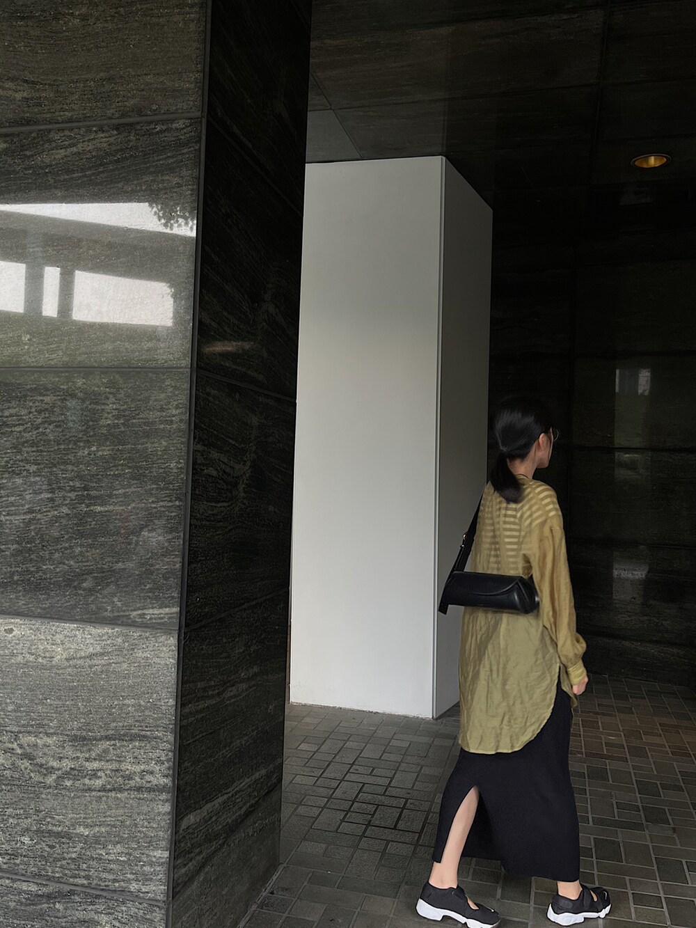 ブラック系のTシャツ/カットソー、ブラック系のスカート、ブラック系のスニーカーを着用したレディースの秋コーディネートの2枚目の写真