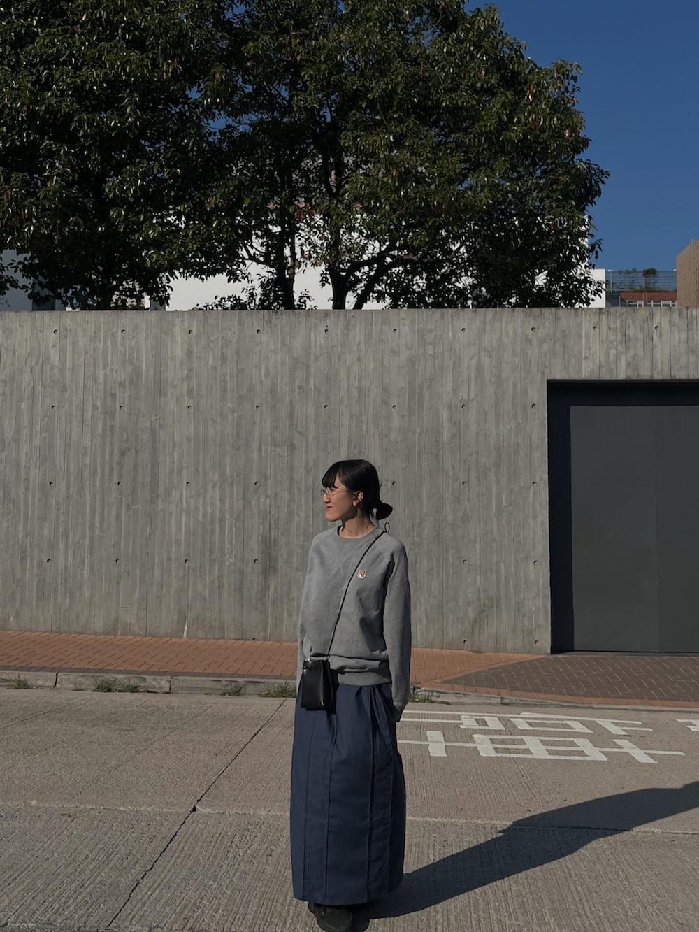 グレー系のスウェット、ブラック系のショルダーバッグ、ブルー系のスカートを着用したレディースの冬コーディネートの2枚目の写真