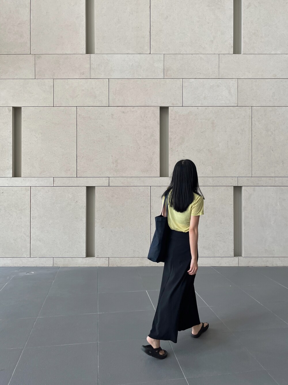 ブルー系のトートバッグ、ブラック系のスカート、ブラック系のサンダルを着用したレディースの夏コーディネートの2枚目の写真