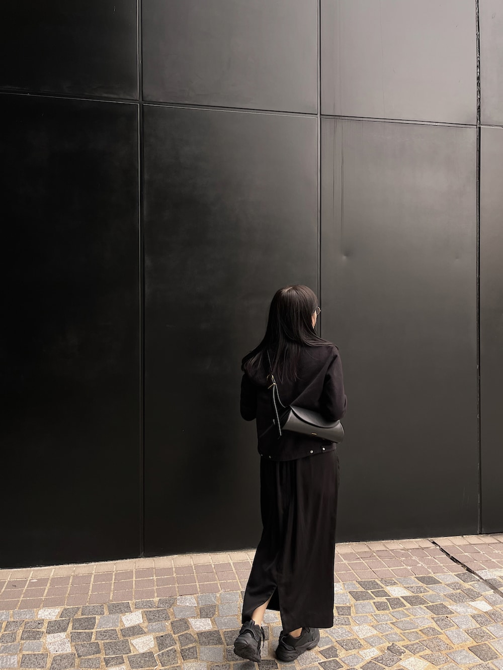 ブラック系のワンピース/ドレス、ブラック系のショルダーバッグ、ブラック系のスニーカーを着用したレディースの秋コーディネートの2枚目の写真