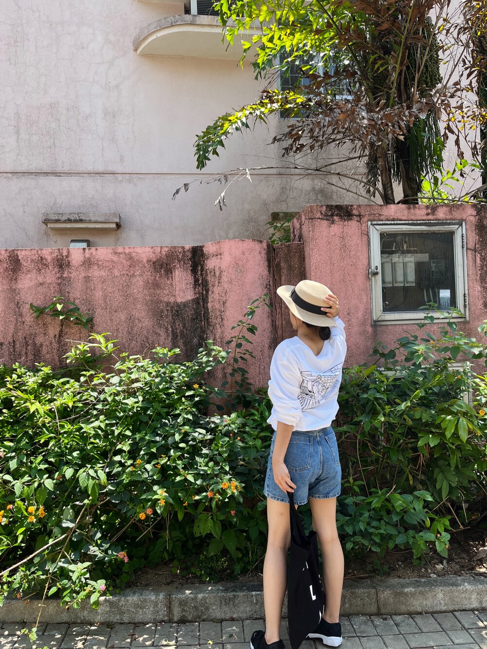 ホワイト系のTシャツ/カットソー、ブルー系のデニムパンツ、ブラック系のバッグを着用したレディースの春コーディネートの2枚目の写真