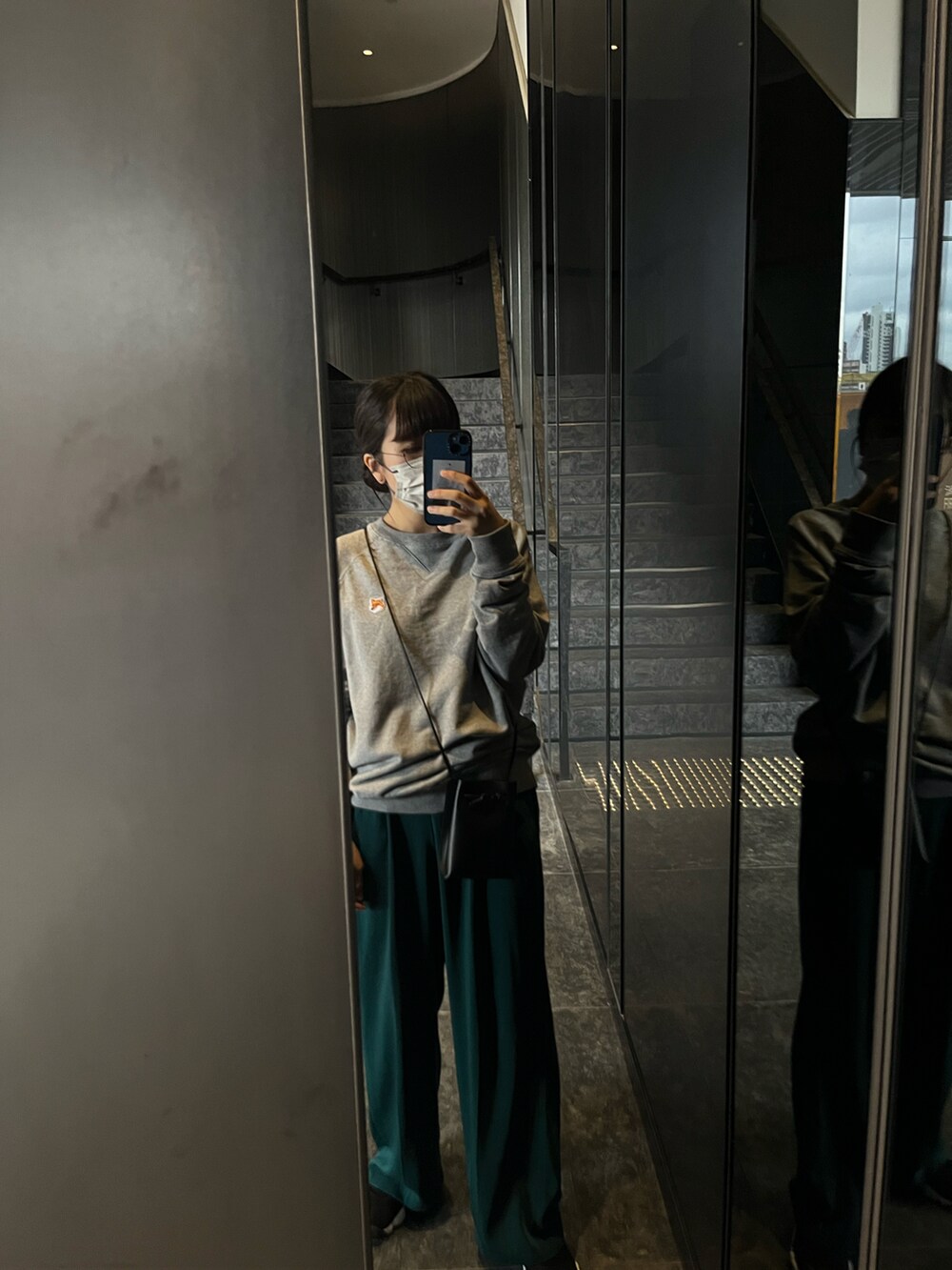 グレー系のスウェット、ブラック系のショルダーバッグ、グリーン系のその他パンツを着用したレディースの春コーディネートの3枚目の写真