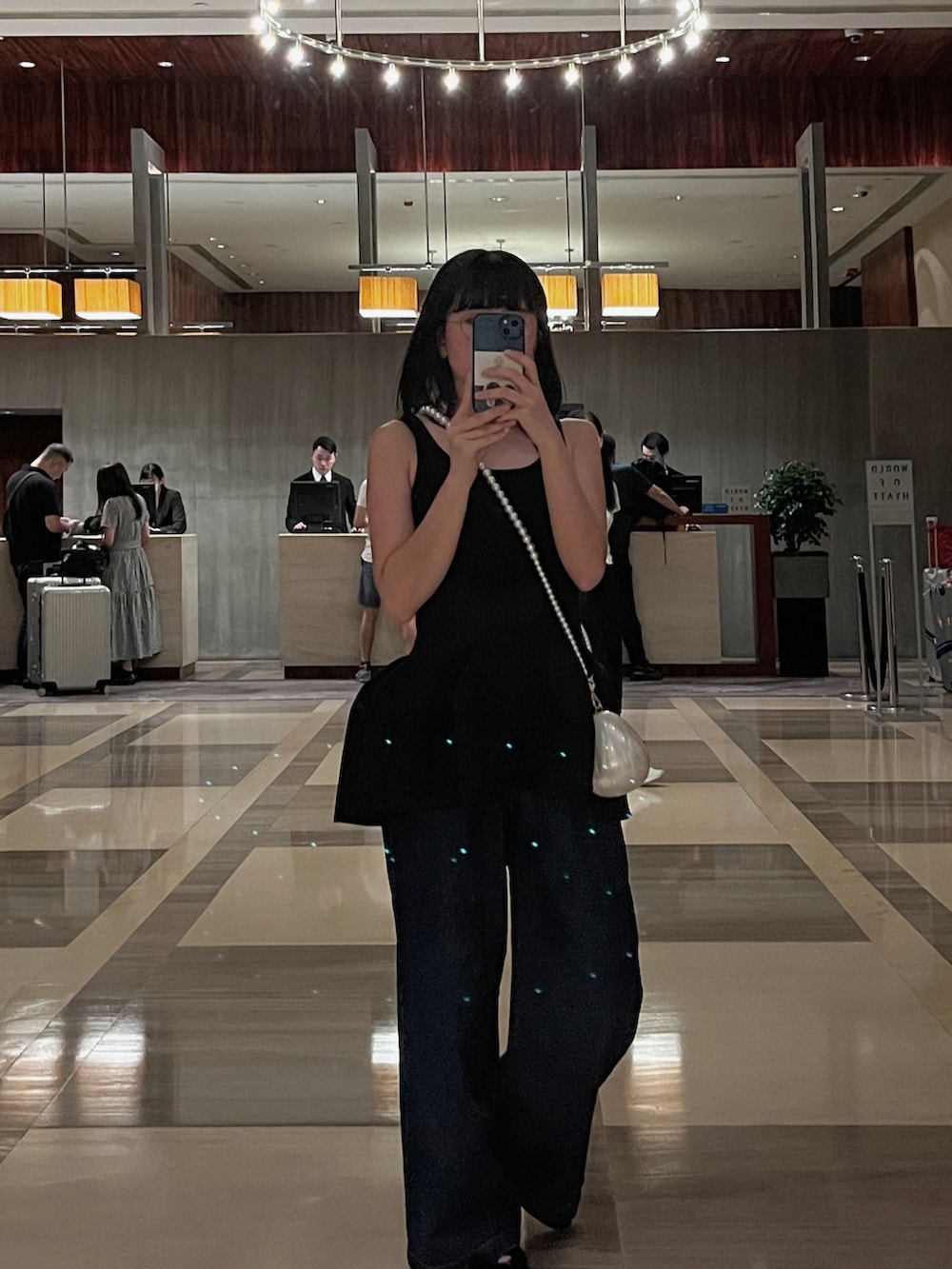 ブラック系のニット/セーター、ホワイト系のバッグ、ブルー系のデニムパンツを着用したレディースの夏コーディネートの3枚目の写真