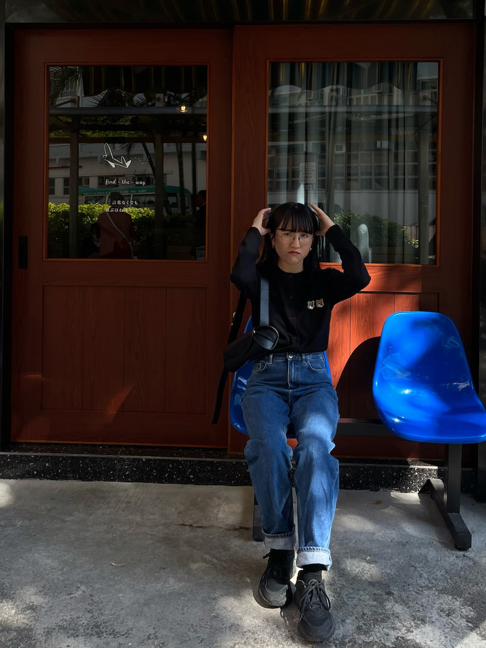 ブラック系のカーディガン/ボレロ、ブラック系のショルダーバッグ、ブルー系のデニムパンツを着用したレディースの冬コーディネートの2枚目の写真