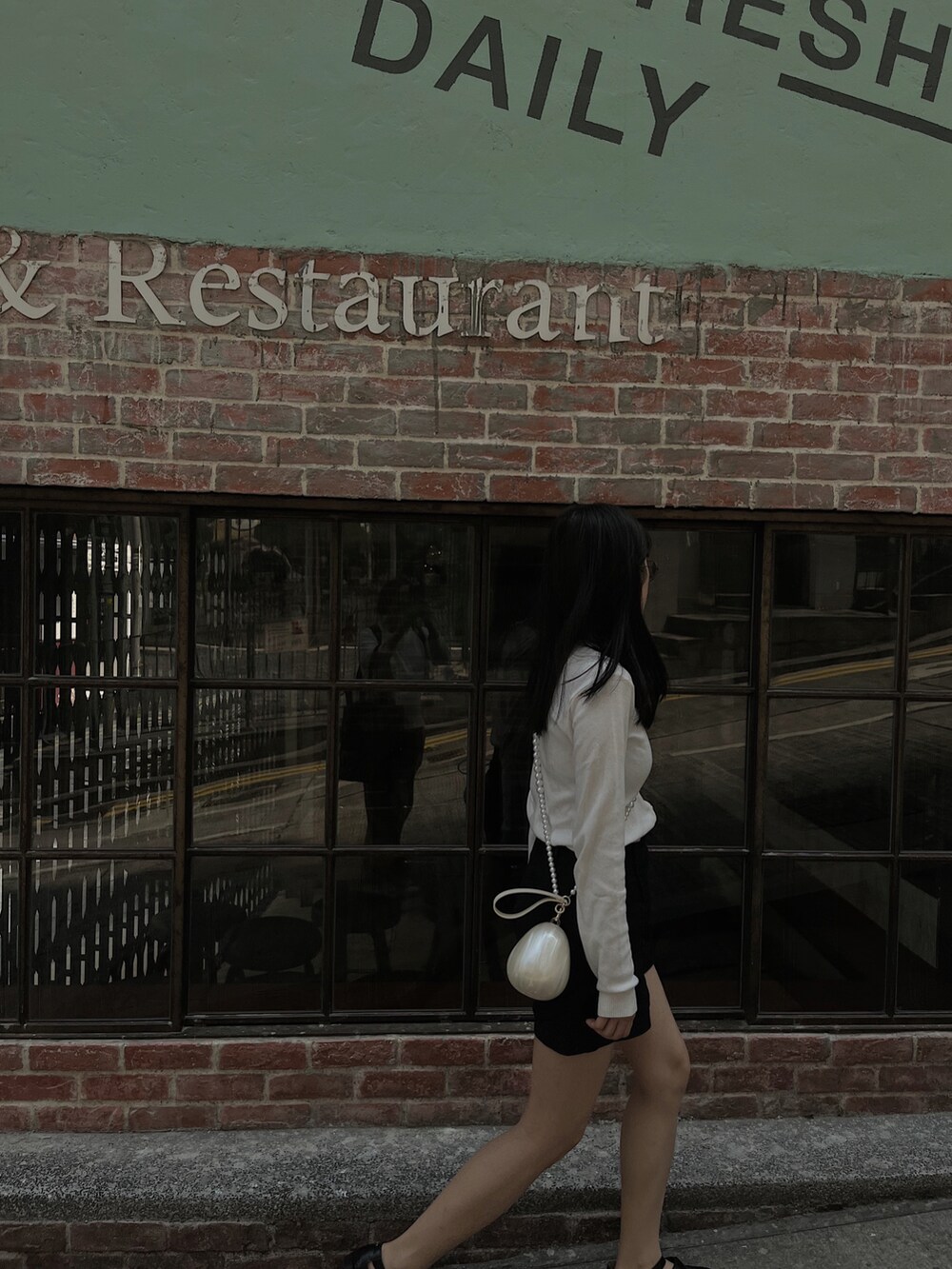 ホワイト系のカーディガン/ボレロ、ブラック系のパンツ、ブラック系のトートバッグを着用したレディースの春コーディネートの2枚目の写真