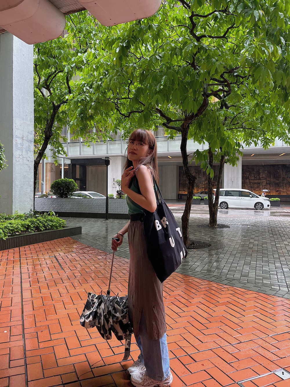 グリーン系のトップス、グレー系のスカート、ブルー系のデニムパンツを着用したレディースの春コーディネートの2枚目の写真