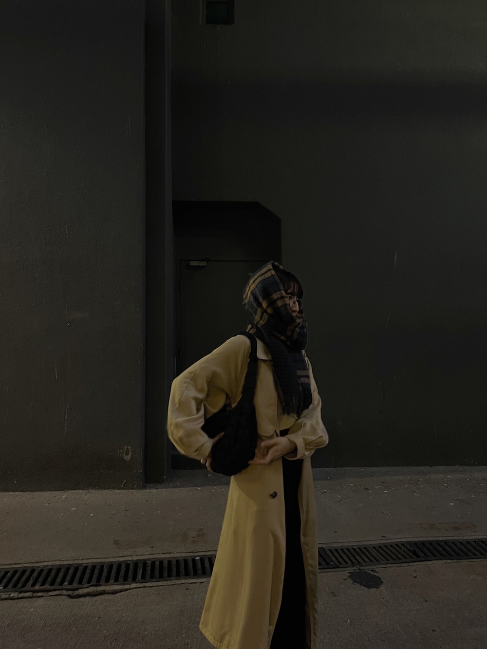 ベージュ系のトレンチコート、ブラック系のバッグ、ブラック系のスニーカーを着用したレディースの冬コーディネートの2枚目の写真