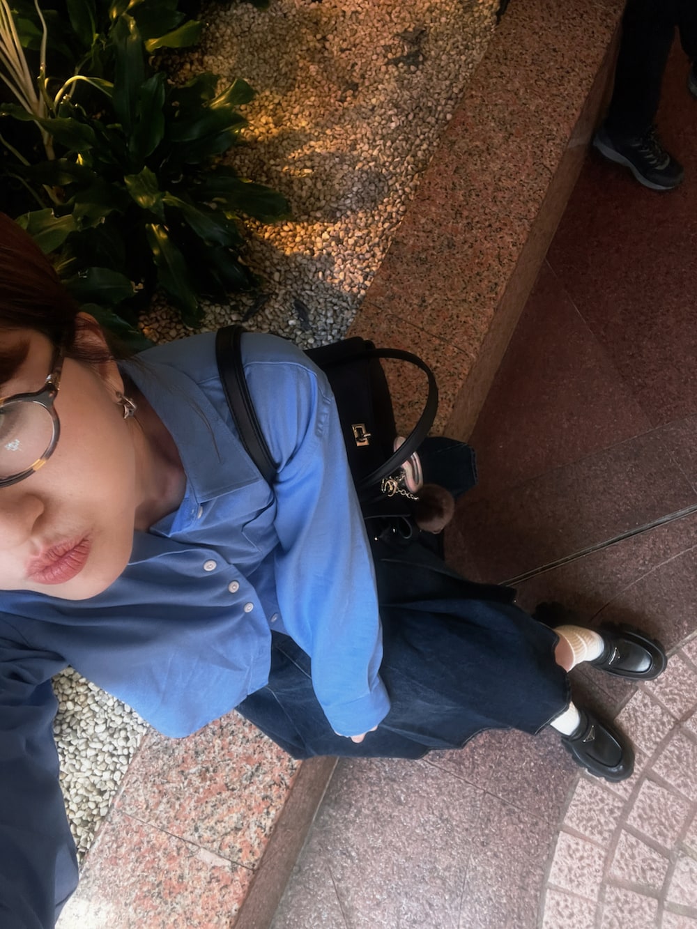 ブルー系のシャツ/ブラウス、ブラック系のローファー、ブラック系のハンドバッグを着用したレディースの秋コーディネートの2枚目の写真