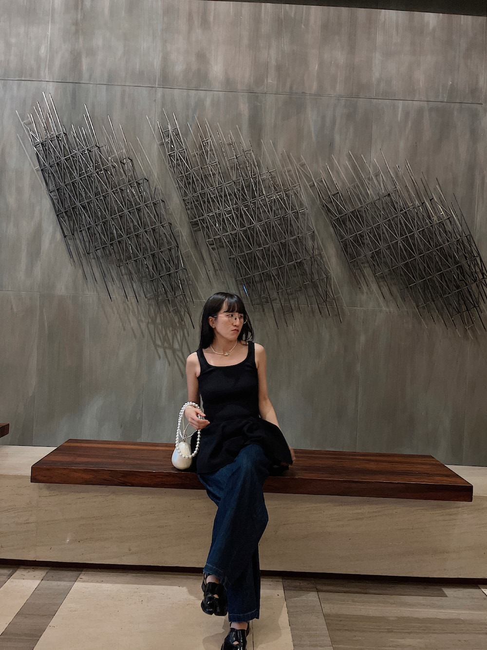 ブラック系のニット/セーター、ホワイト系のバッグ、ブルー系のデニムパンツを着用したレディースの夏コーディネートの2枚目の写真