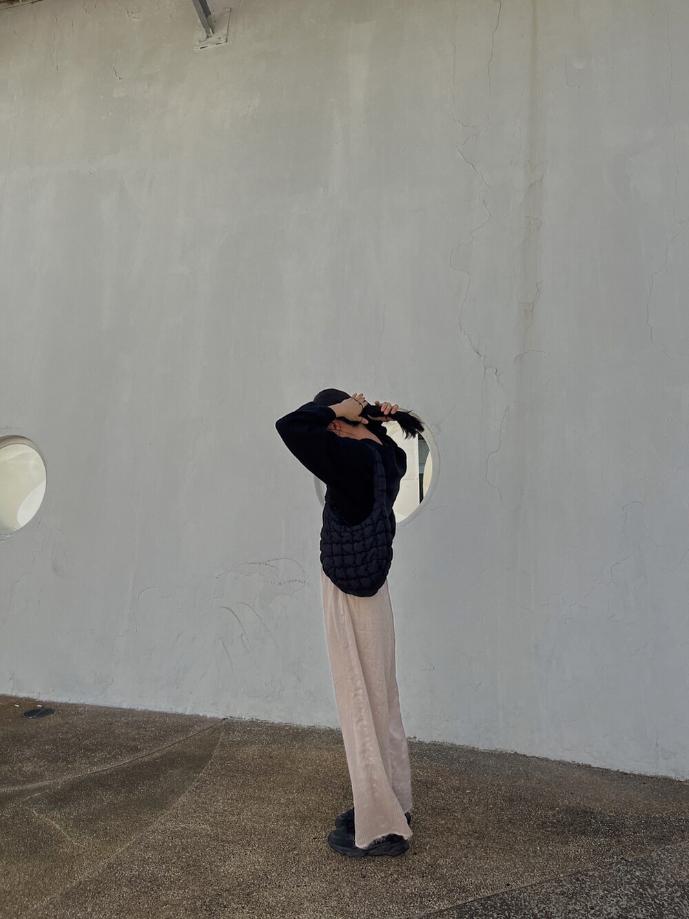 ブラック系のジャージ、ブラック系のバッグ、ブラック系のスニーカーを着用したレディースの冬コーディネートの2枚目の写真