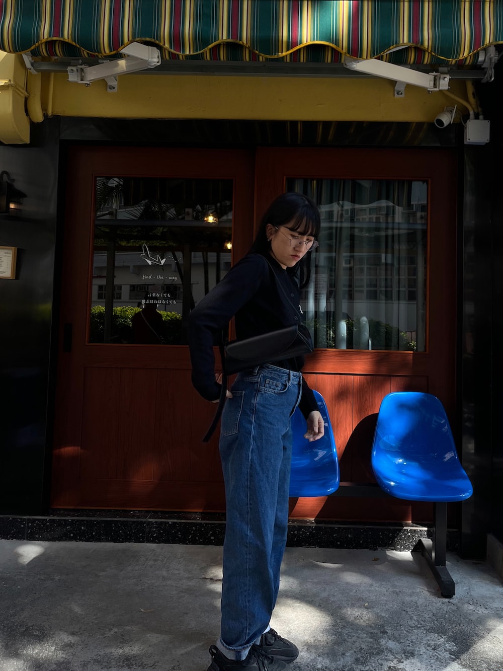 ブラック系のカーディガン/ボレロ、ブラック系のショルダーバッグ、ブルー系のデニムパンツを着用したレディースの冬コーディネートの3枚目の写真