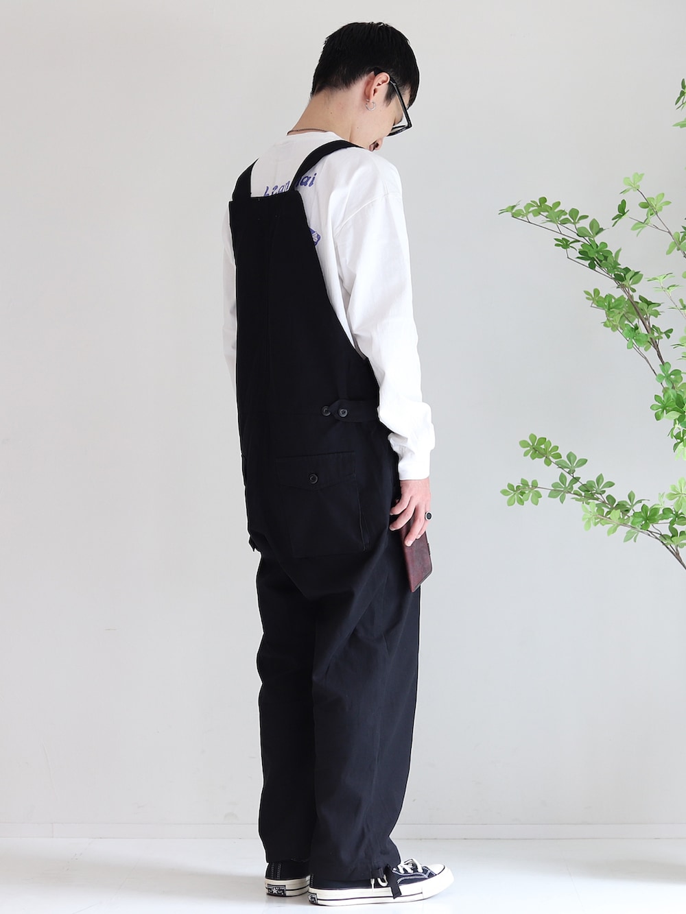 ブラック系のサロペット/オーバーオール、ブラック系のスニーカー、レッド系の財布を着用したメンズの秋コーディネートの2枚目の写真