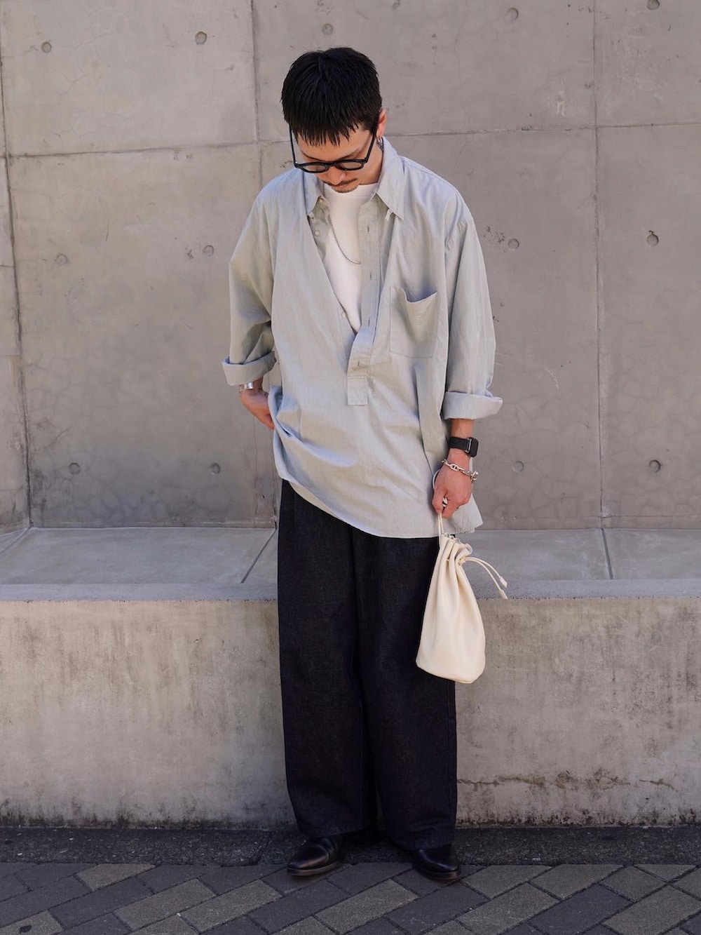 ホワイト系のショルダーバッグ、ブラック系のシューズ、ブルー系のデニムパンツを着用したメンズの秋コーディネートの2枚目の写真