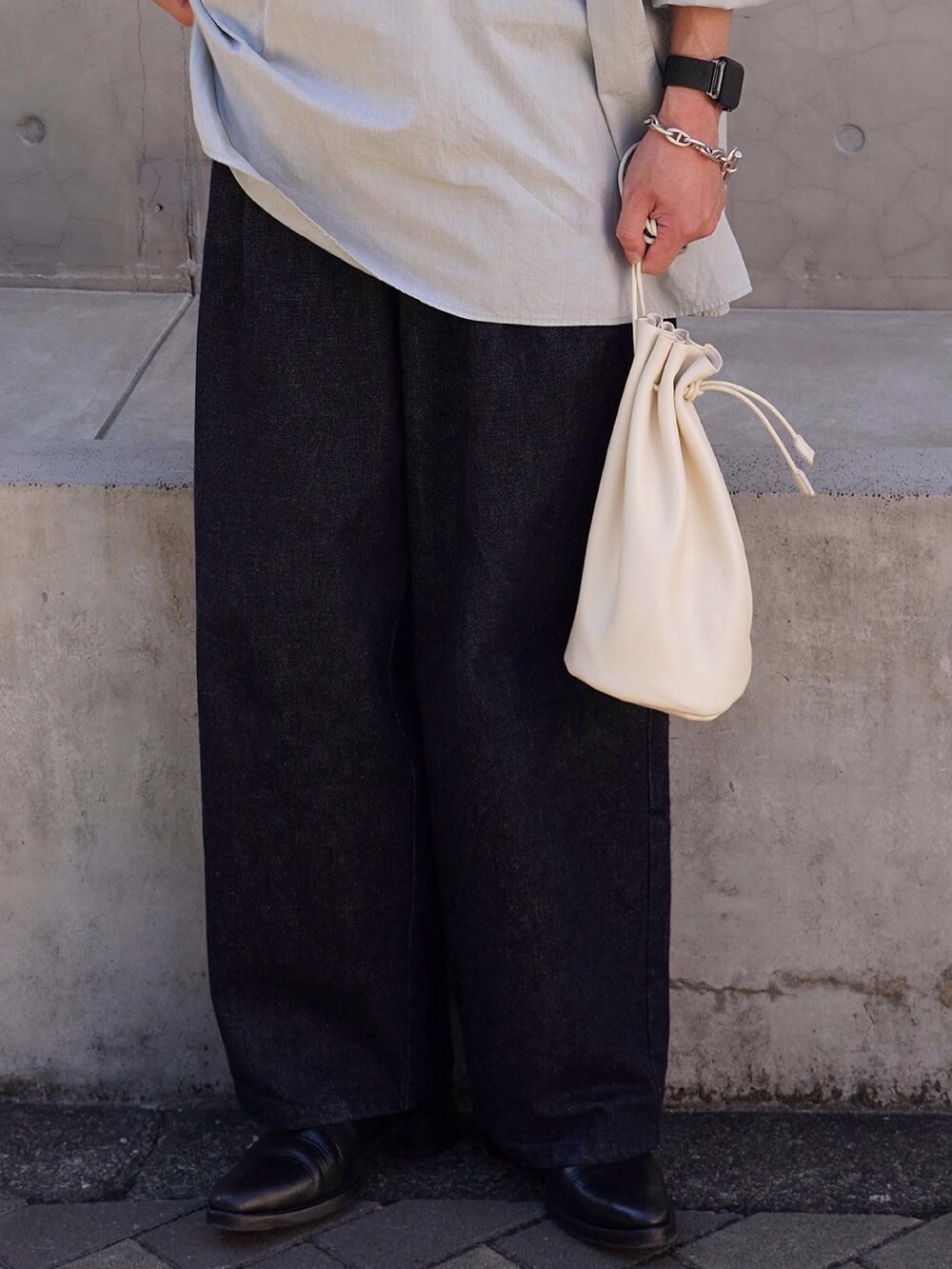 ホワイト系のショルダーバッグ、ブラック系のシューズ、ブルー系のデニムパンツを着用したメンズの秋コーディネートの4枚目の写真