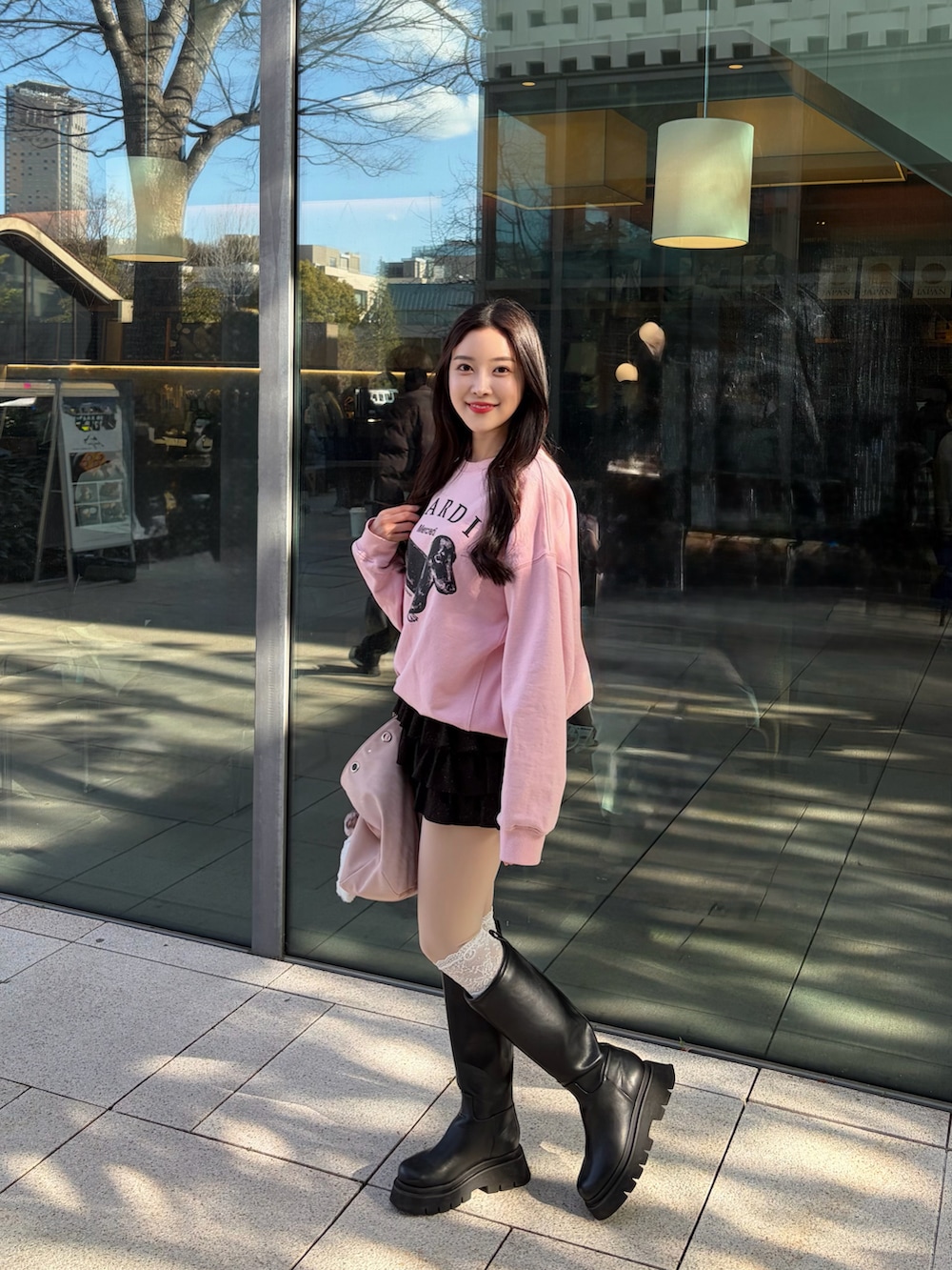 ブラック系のブーツ、ブラック系のスカート、ピンク系のスウェットを着用したレディースの春コーディネートの2枚目の写真