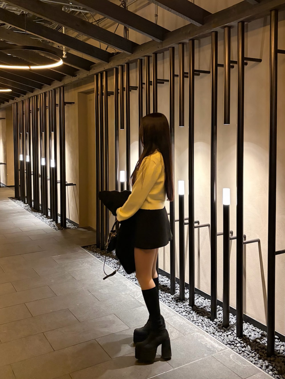 ブラック系のブーツ、イエロー系のカーディガン/ボレロ、ブラック系のスカートを着用したレディースの春コーディネートの3枚目の写真