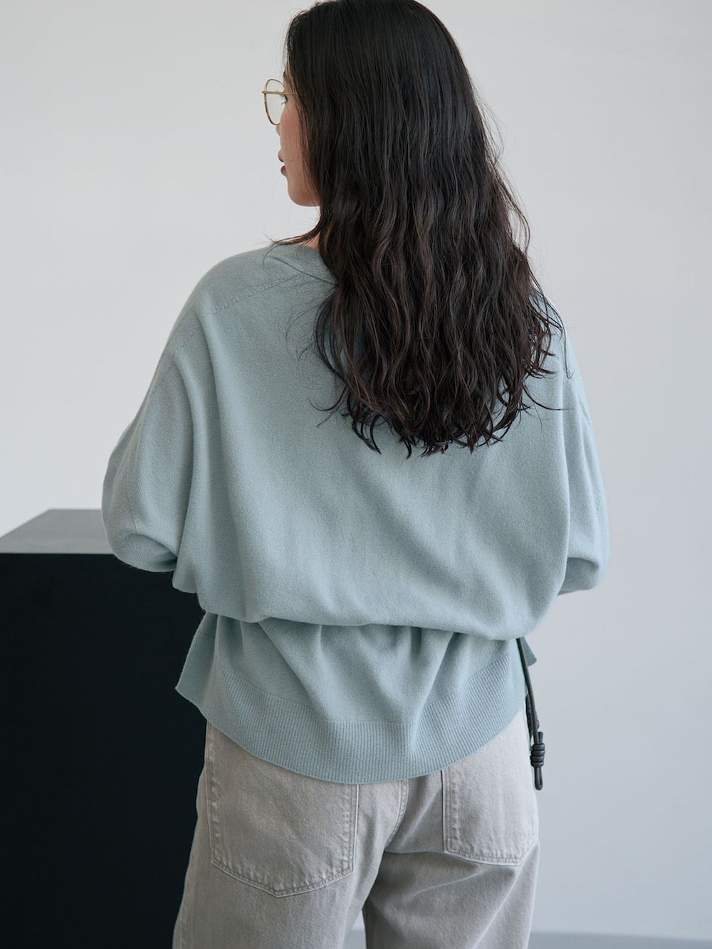 グレー系のデニムパンツ、ブルー系のカーディガン/ボレロ、ブラック系のクラッチバッグを着用したレディースの秋コーディネートの5枚目の写真