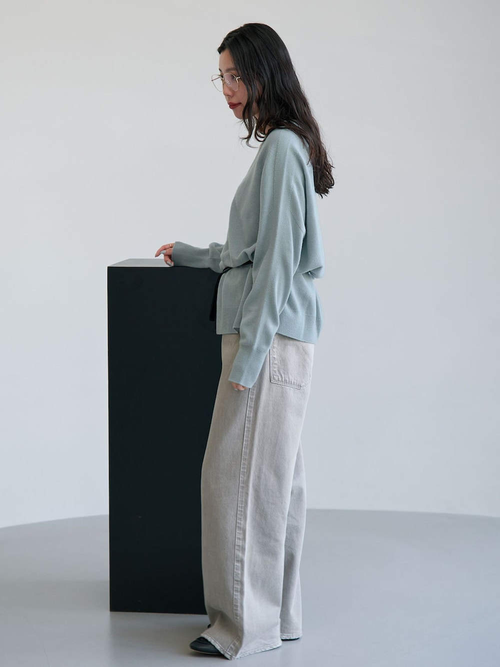 グレー系のデニムパンツ、ブルー系のカーディガン/ボレロ、ブラック系のクラッチバッグを着用したレディースの秋コーディネートの2枚目の写真