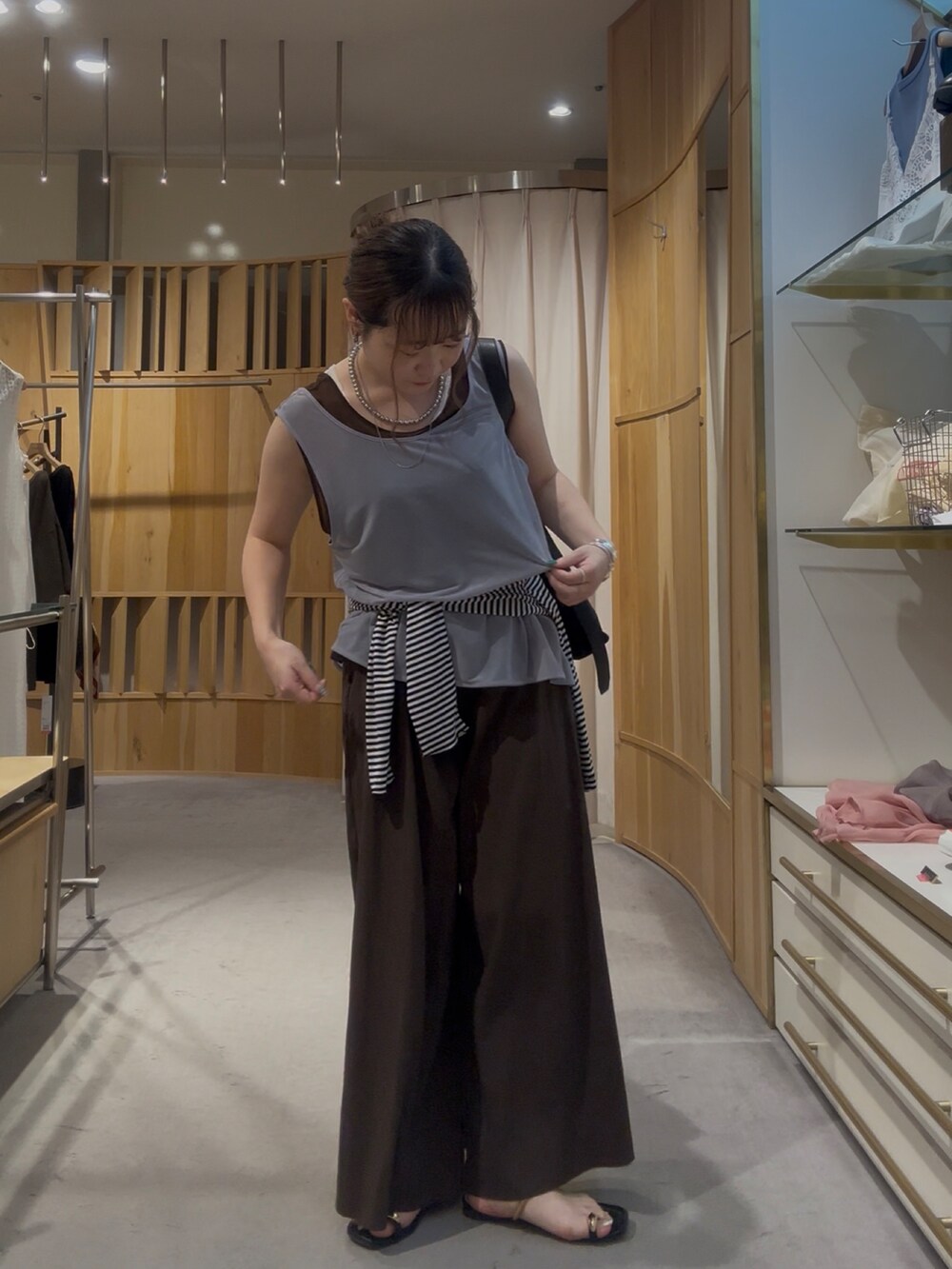 グレー系のタンクトップ、ブラック系のトートバッグ、ブラウン系のその他パンツを着用したレディースの夏コーディネートの2枚目の写真
