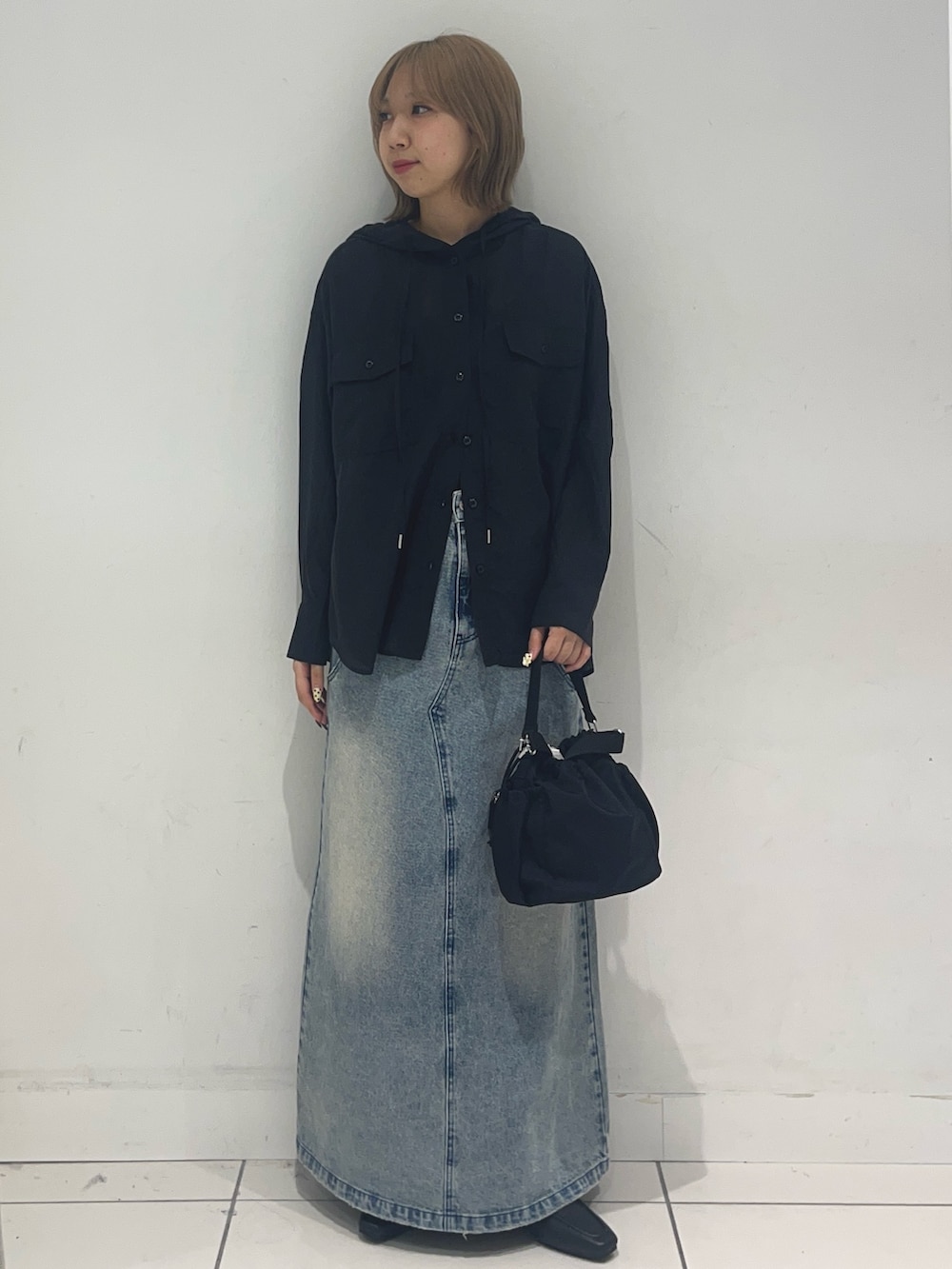 ブラック系のシャツ/ブラウス、ブルー系のスカート、ブラック系のハンドバッグを着用したレディースの春コーディネートの2枚目の写真