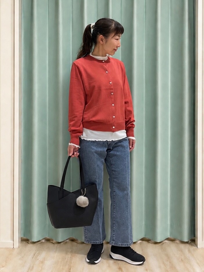レッド系のカーディガン/ボレロ、ホワイト系のTシャツ/カットソー、ブルー系のデニムパンツを着用したレディースの秋コーディネートの4枚目の写真