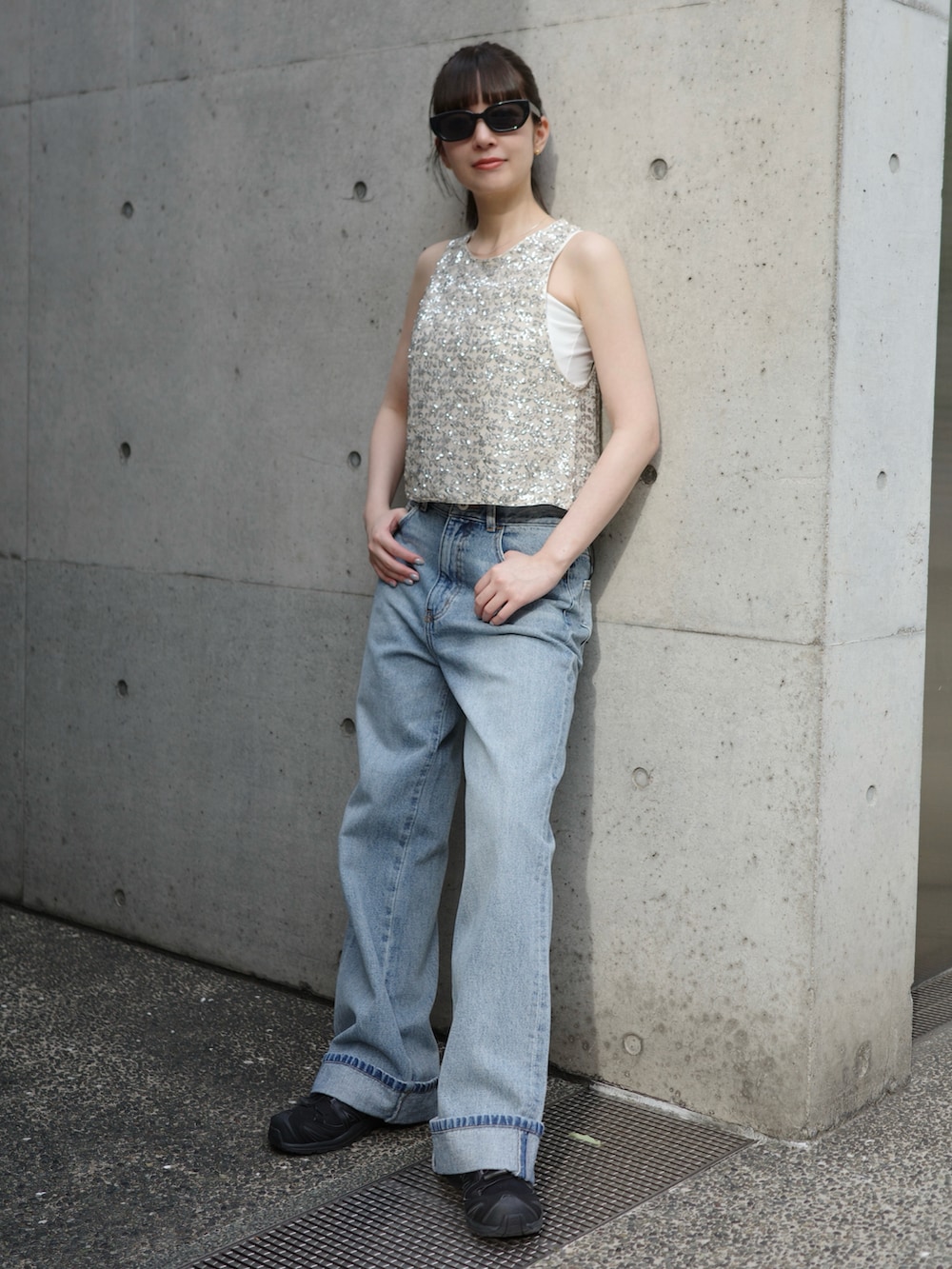 シルバー系のトップス、ブルー系のデニムパンツ、ブラック系のスニーカーを着用したレディースの夏コーディネートの2枚目の写真