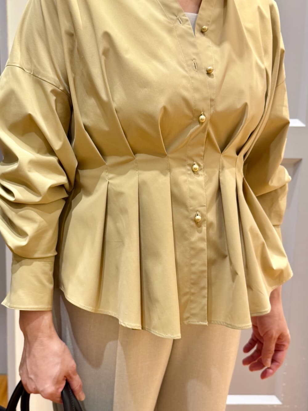 イエロー系のシャツ/ブラウス、ベージュ系のその他パンツ、ブラック系のパンプスを着用したレディースの秋コーディネートの7枚目の写真