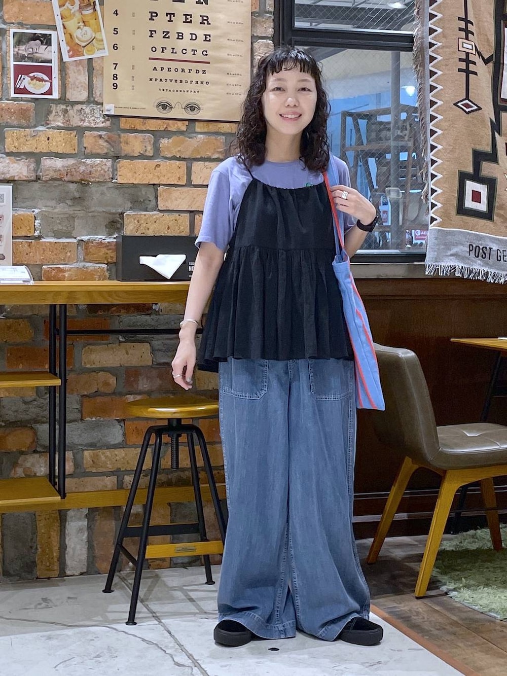 ブルー系のトートバッグ、ブラック系のキャミソール、ブルー系のデニムパンツを着用したレディースの春コーディネートの5枚目の写真