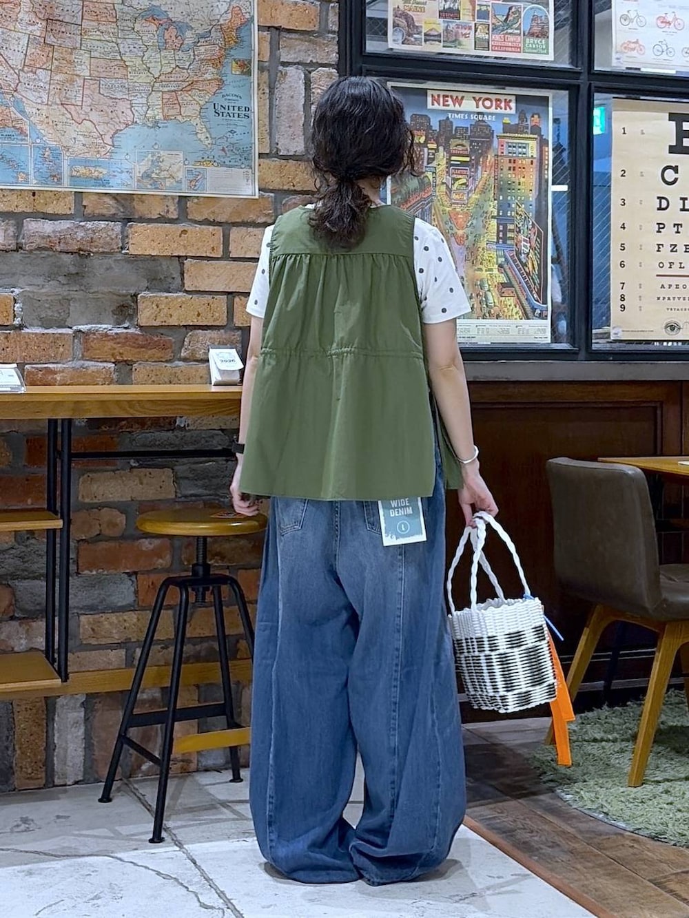 ブルー系のデニムパンツ、グリーン系のベスト、その他のかごバッグを着用したレディースの夏コーディネートの3枚目の写真