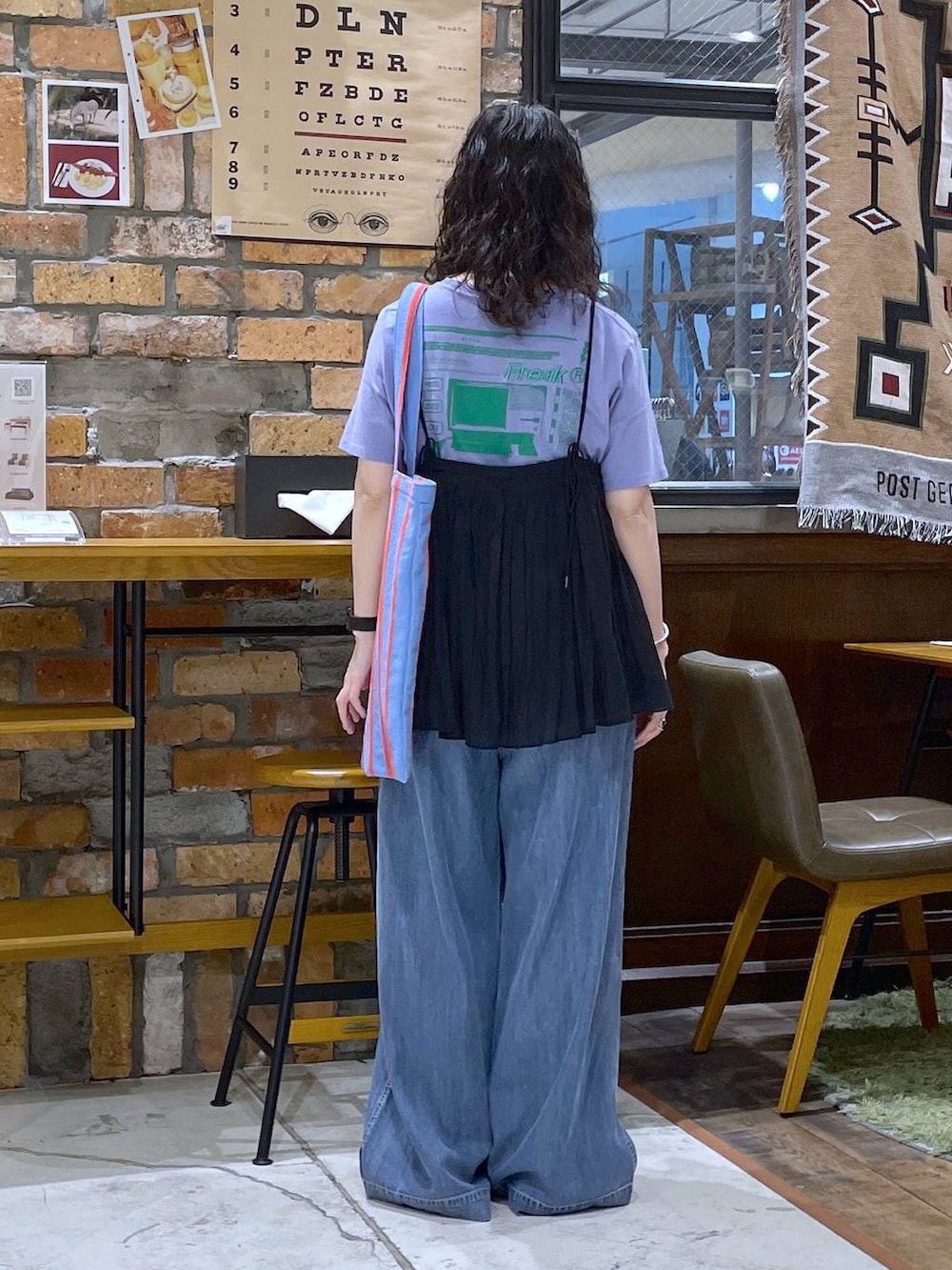 ブルー系のトートバッグ、ブラック系のキャミソール、ブルー系のデニムパンツを着用したレディースの春コーディネートの3枚目の写真