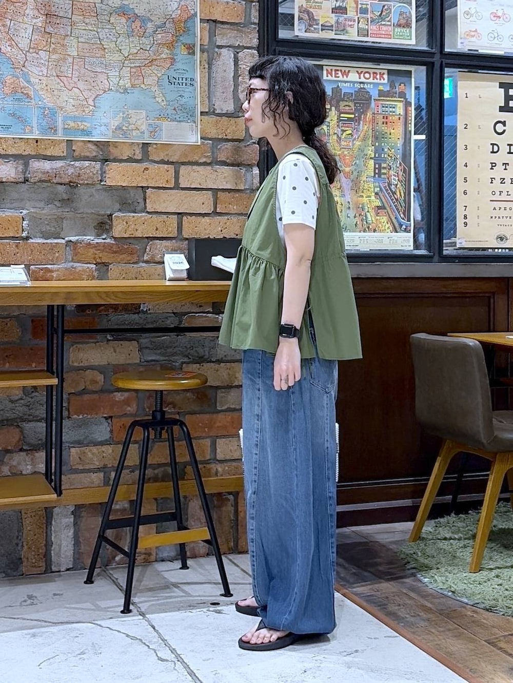 ブルー系のデニムパンツ、グリーン系のベスト、その他のかごバッグを着用したレディースの夏コーディネートの2枚目の写真