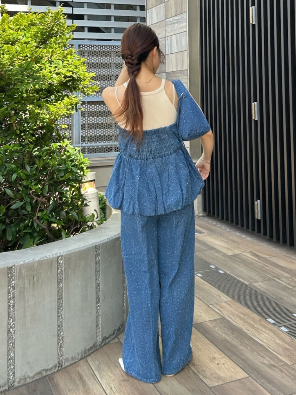 ブルー系のチューブトップ、ブルー系のデニムパンツ、ブルー系のハンドバッグを着用したレディースの夏コーディネートの3枚目の写真