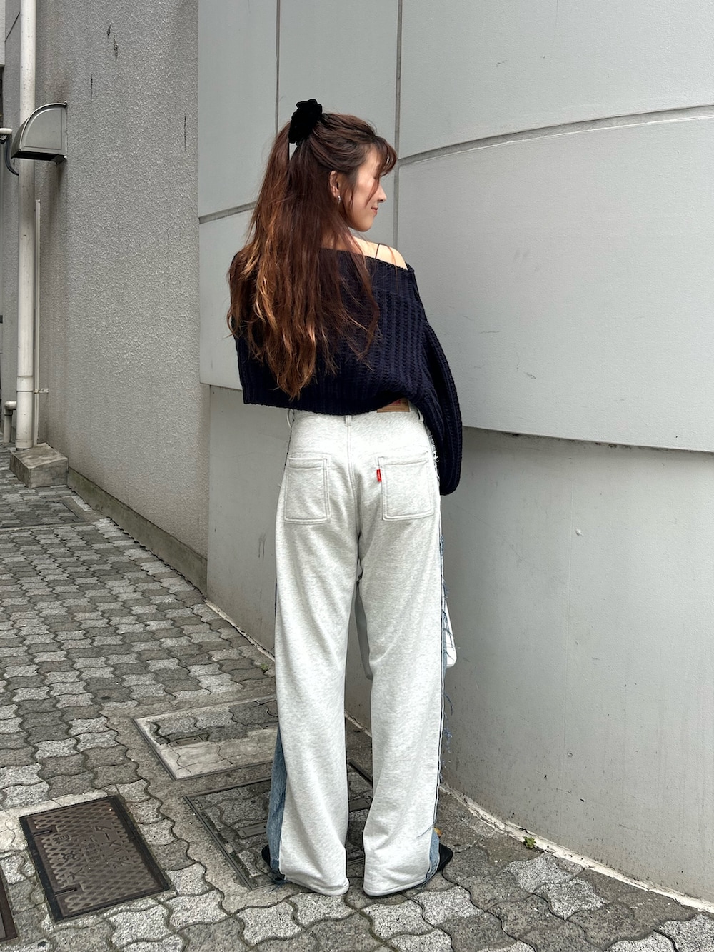 ブルー系のニット/セーター、ブルー系のデニムパンツ、ホワイト系のハンドバッグを着用したレディースの秋コーディネートの4枚目の写真