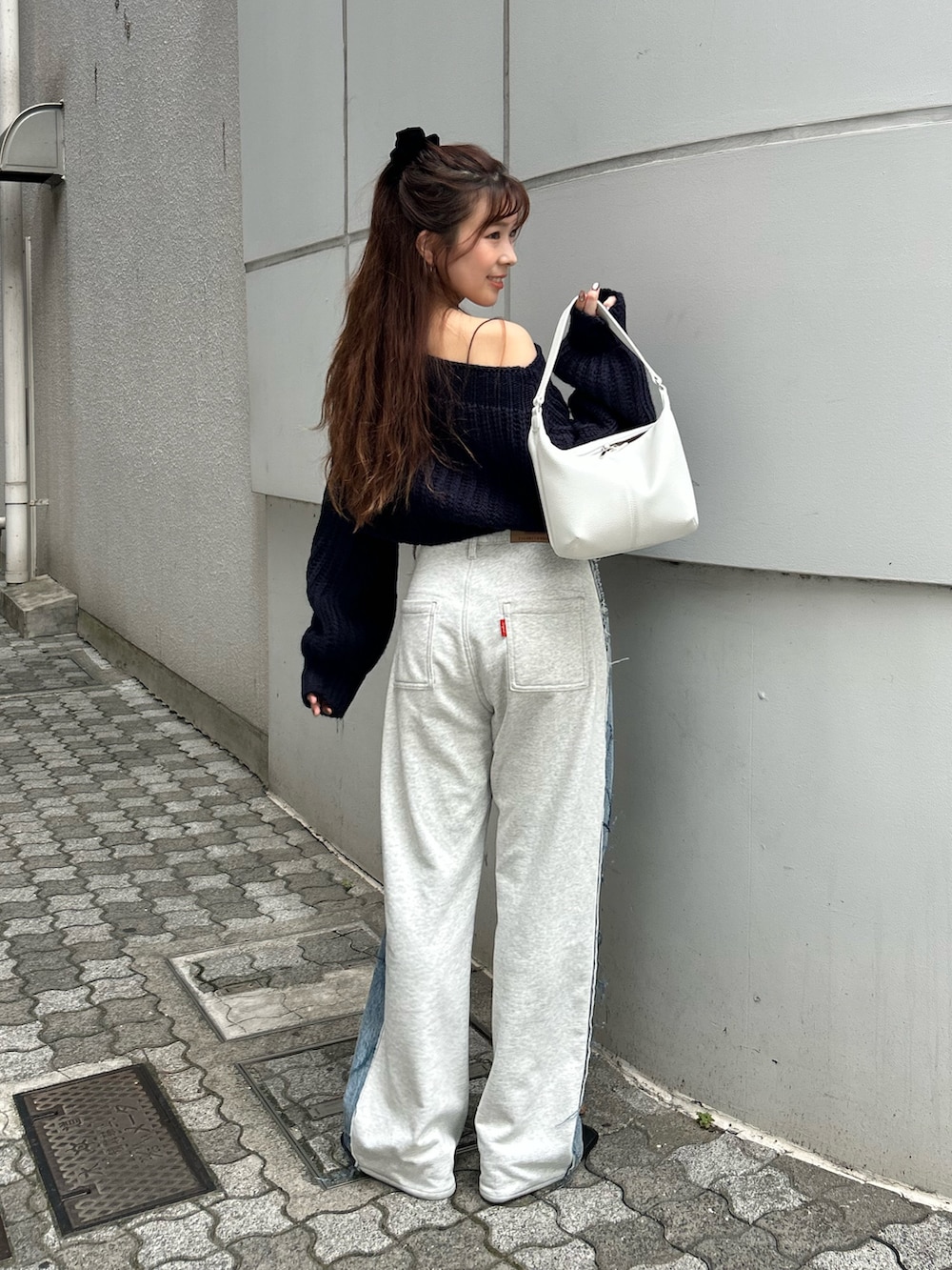 ブルー系のニット/セーター、ブルー系のデニムパンツ、ホワイト系のハンドバッグを着用したレディースの秋コーディネートの5枚目の写真
