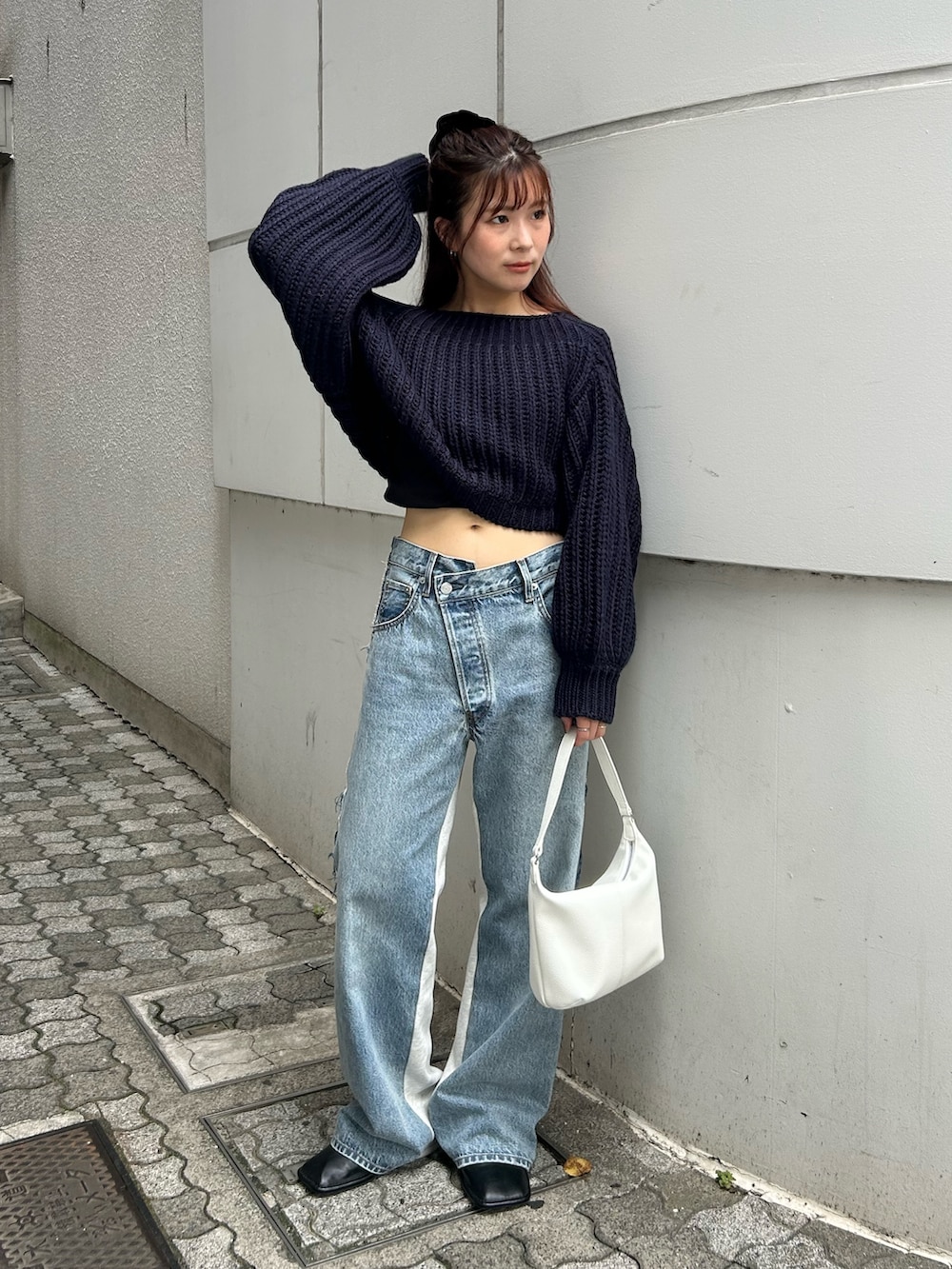 ブルー系のニット/セーター、ブルー系のデニムパンツ、ホワイト系のハンドバッグを着用したレディースの秋コーディネートの2枚目の写真