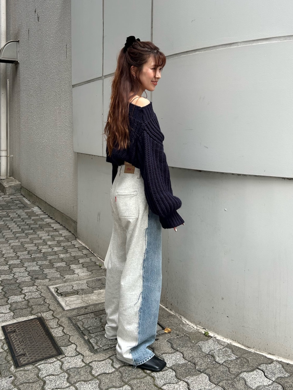 ブルー系のニット/セーター、ブルー系のデニムパンツ、ホワイト系のハンドバッグを着用したレディースの秋コーディネートの3枚目の写真
