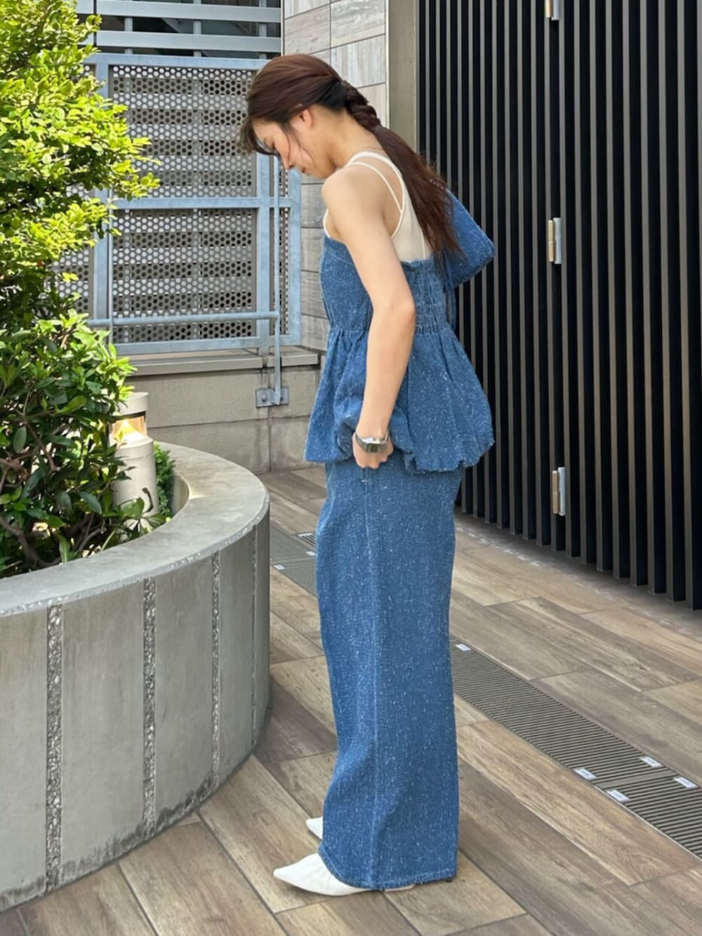ブルー系のチューブトップ、ブルー系のデニムパンツ、ブルー系のハンドバッグを着用したレディースの夏コーディネートの2枚目の写真