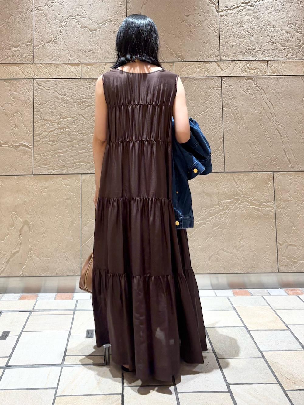 ブラウン系のワンピース、ブラウン系のバッグ、ブルー系のデニムジャケットを着用したレディースの夏コーディネートの5枚目の写真