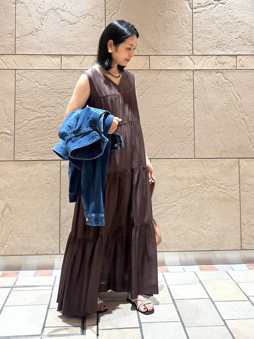 ブラウン系のワンピース、ブラウン系のバッグ、ブルー系のデニムジャケットを着用したレディースの夏コーディネートの2枚目の写真