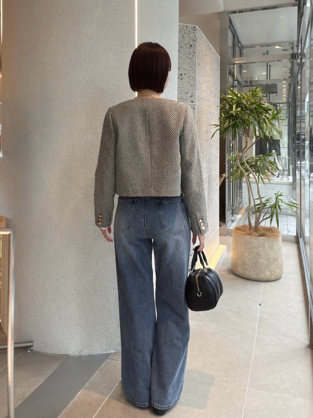 ブラック系のブルゾン、ホワイト系のTシャツ/カットソー、ブルー系のデニムパンツを着用したレディースの秋コーディネートの3枚目の写真