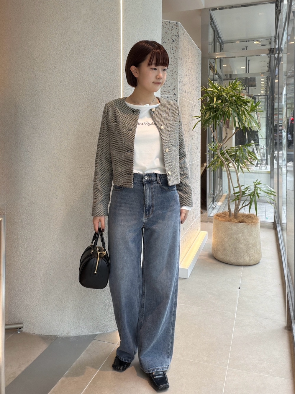 ブラック系のブルゾン、ホワイト系のTシャツ/カットソー、ブルー系のデニムパンツを着用したレディースの秋コーディネートの6枚目の写真