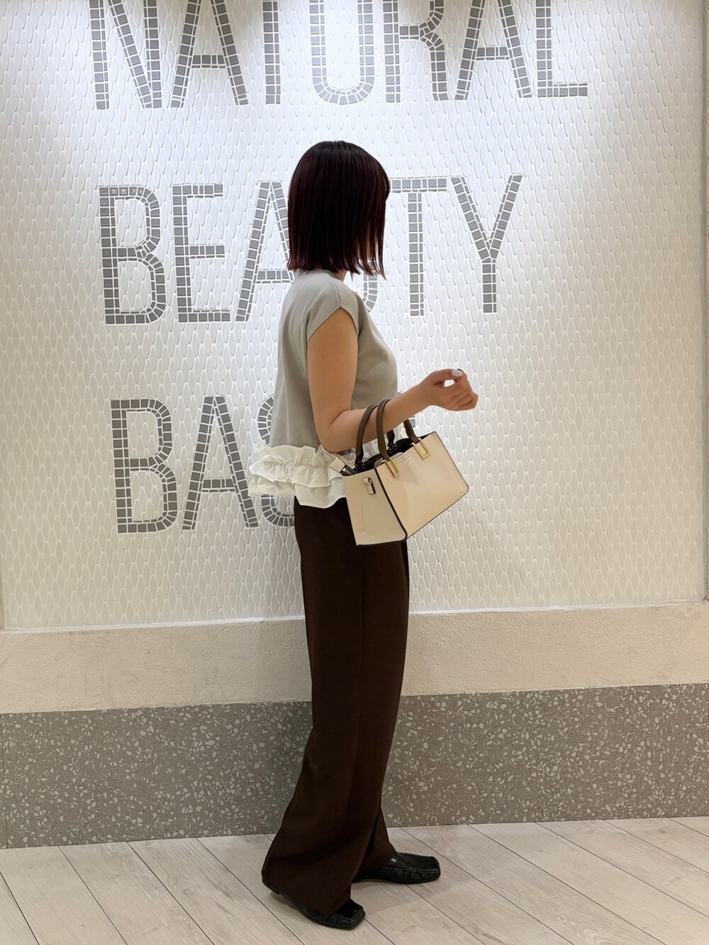 グレー系のベスト、ブラウン系のその他パンツ、ホワイト系のトートバッグを着用したレディースの夏コーディネートの2枚目の写真