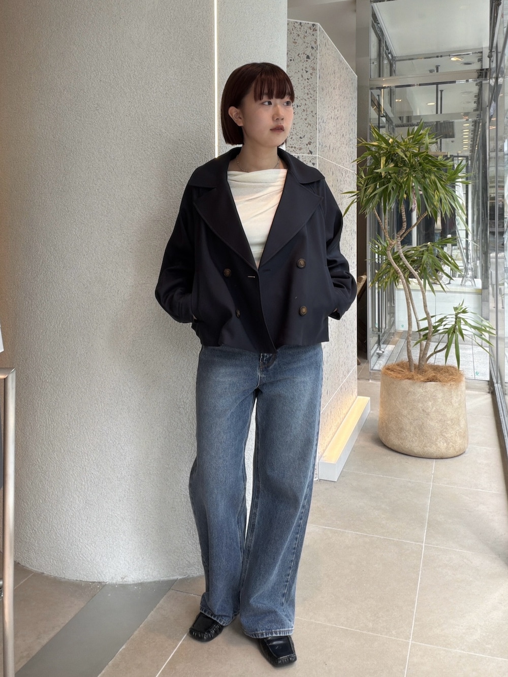 ブルー系のトレンチコート、ホワイト系のTシャツ/カットソー、ブルー系のデニムパンツを着用したレディースの秋コーディネートの5枚目の写真