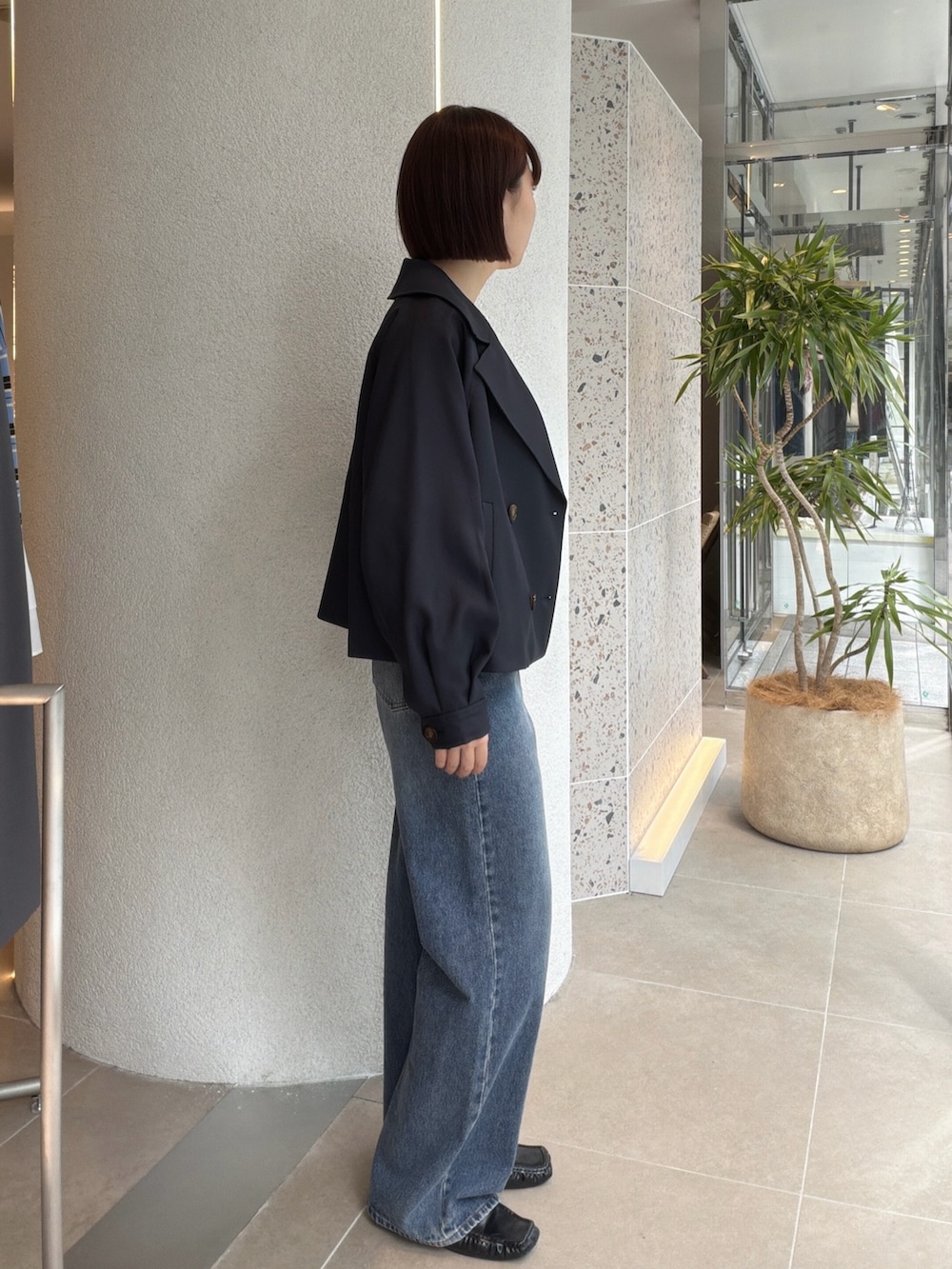 ブルー系のトレンチコート、ホワイト系のTシャツ/カットソー、ブルー系のデニムパンツを着用したレディースの秋コーディネートの2枚目の写真