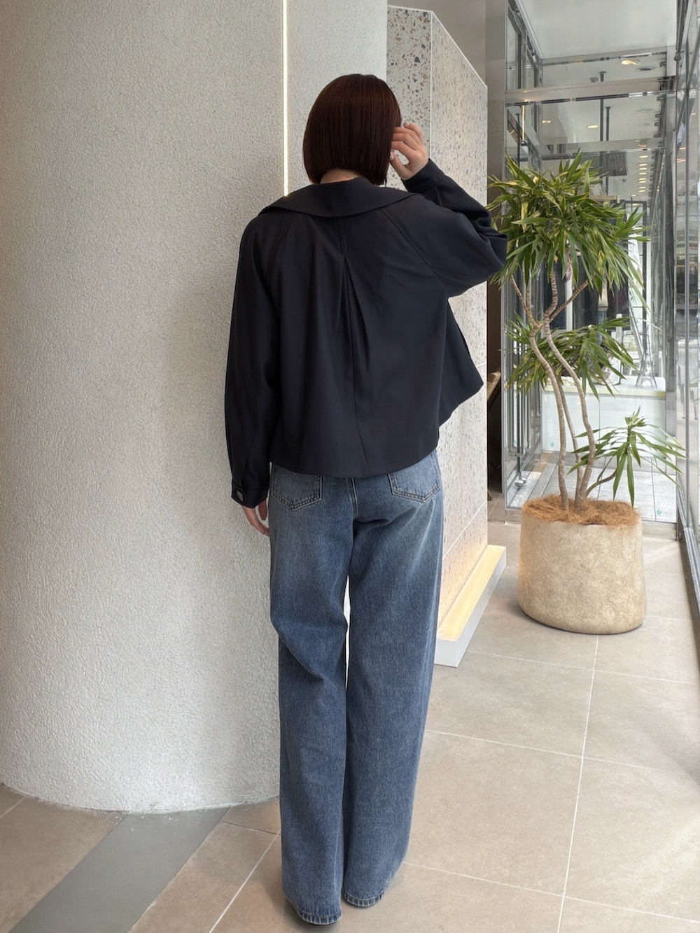 ブルー系のトレンチコート、ホワイト系のTシャツ/カットソー、ブルー系のデニムパンツを着用したレディースの秋コーディネートの3枚目の写真