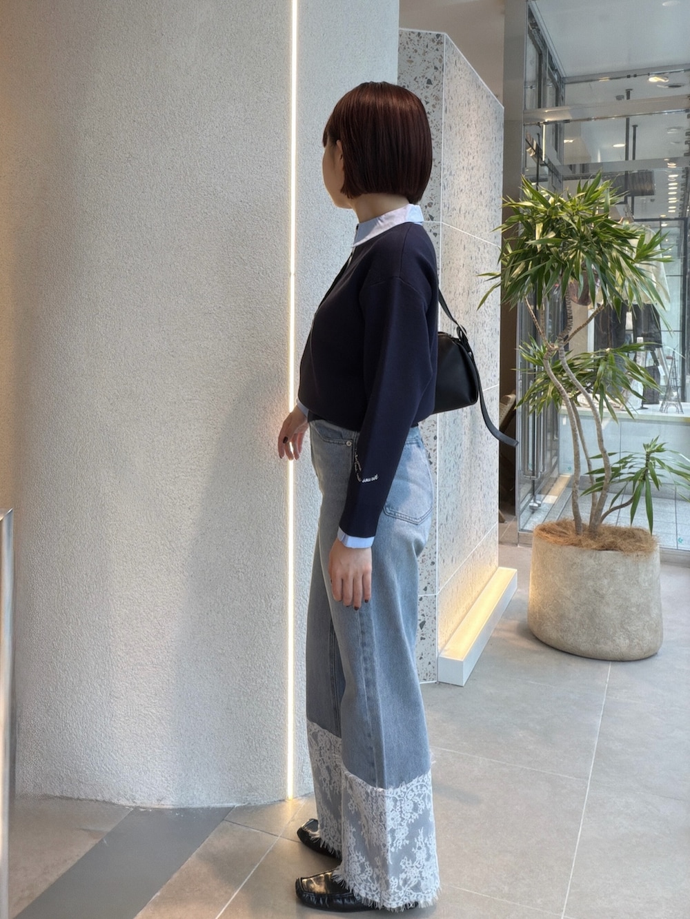 ブルー系のニット/セーター、ブラック系のショルダーバッグ、ブルー系のデニムパンツを着用したレディースの秋コーディネートの4枚目の写真